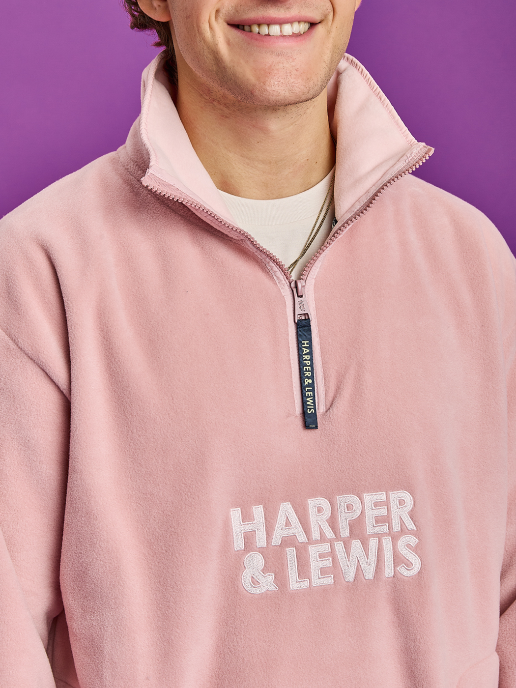 Detail shot of the embroidered stacked logo on the front and the navy zip puller.