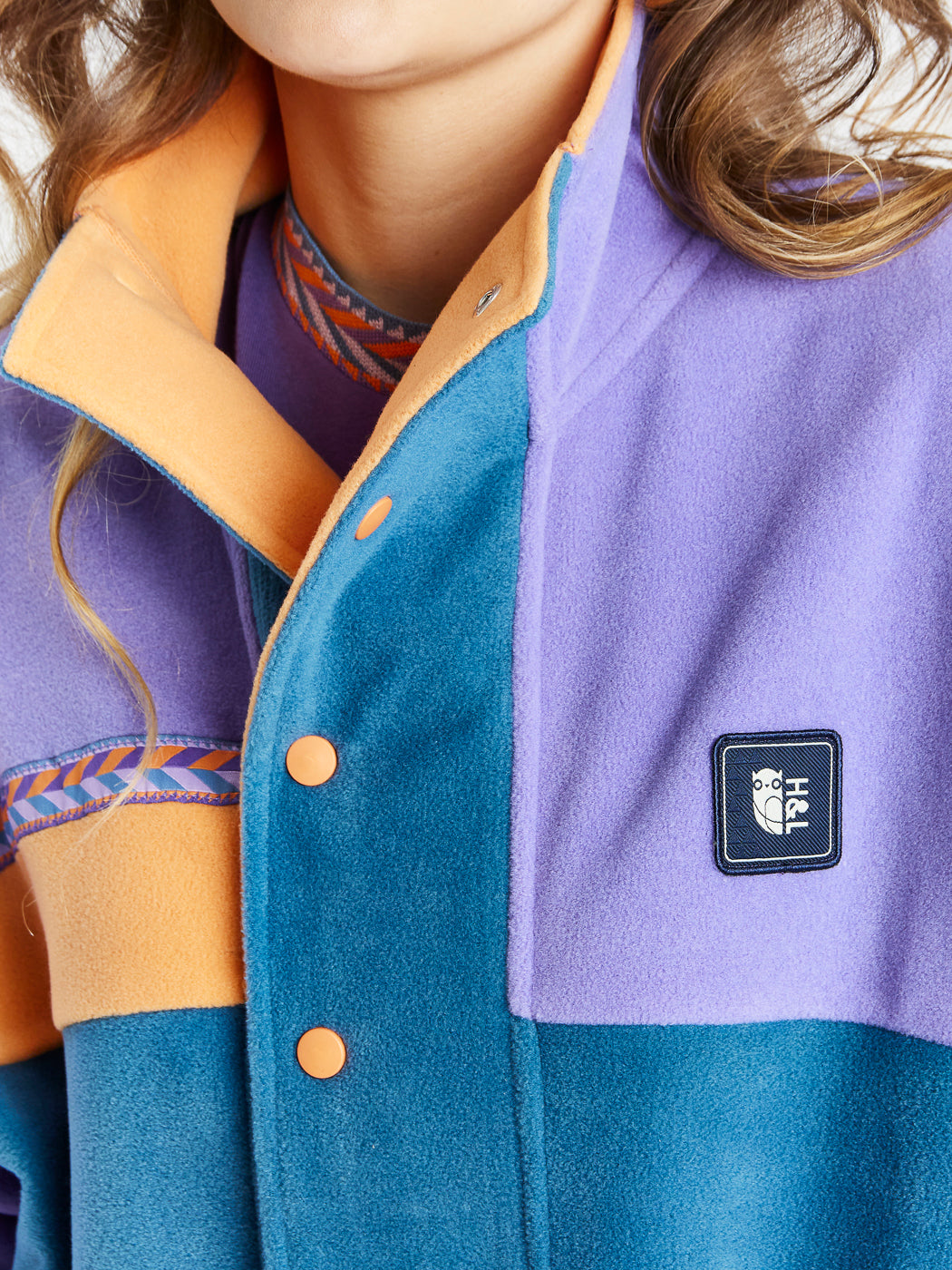 details of the apricot buttons and the woven branded badge of the womens fleece jacket.