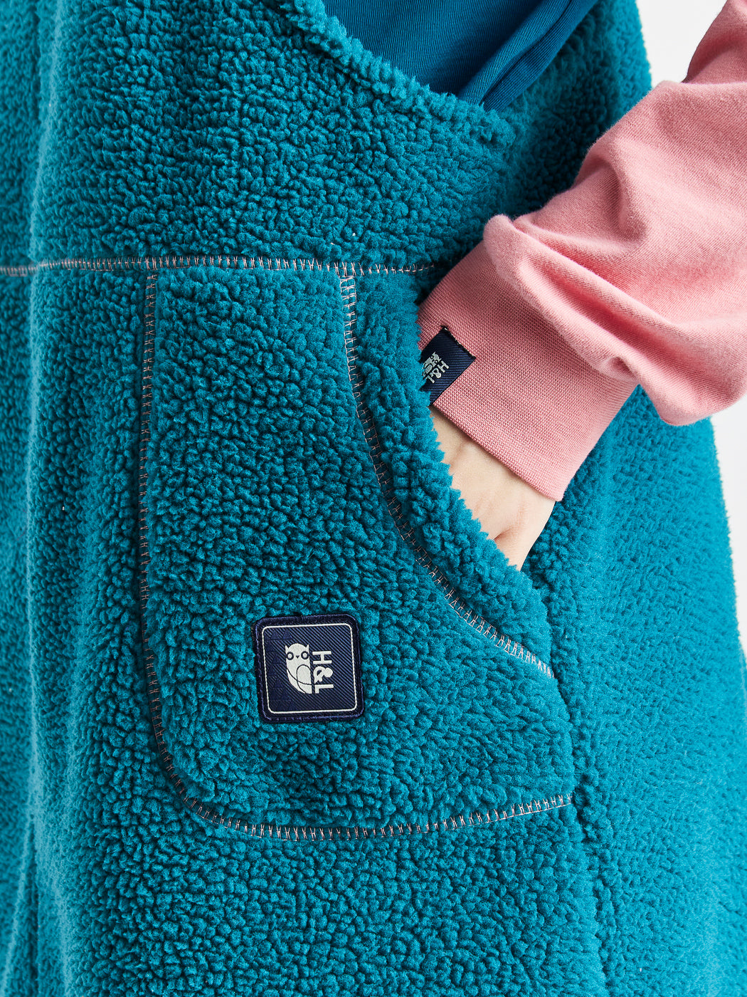 Harper and Lewis Navy branded badge shown on the pocket of the fluffy Sherpa pinafore dress.