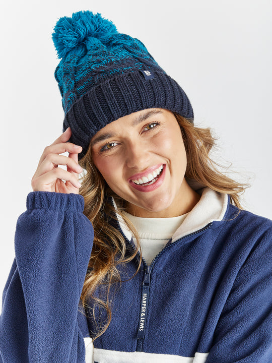 The beanie is finished with a luxury pom pom and a branded woven tab in navy, adding a stylish and modern touch.