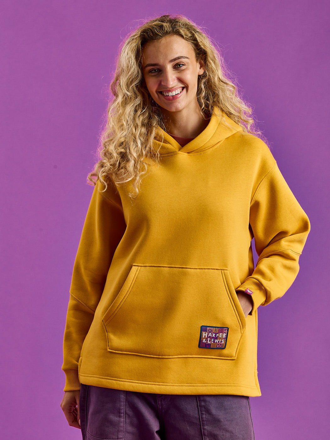 Female wears this unisex hoodie this features a woven branded tab on the cuff and back neck, this hoodie adds a unique accent to its overall design.