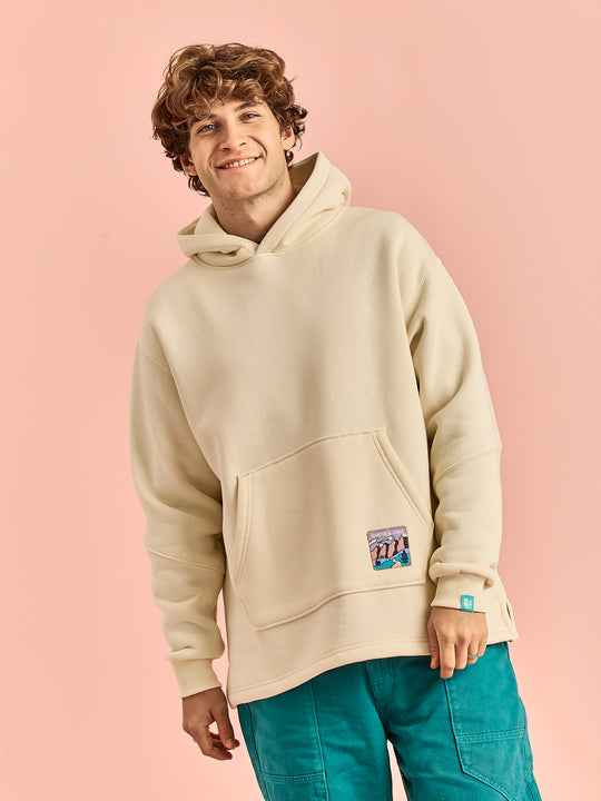 Male Model wearing the hooded sweater in a cream like colour