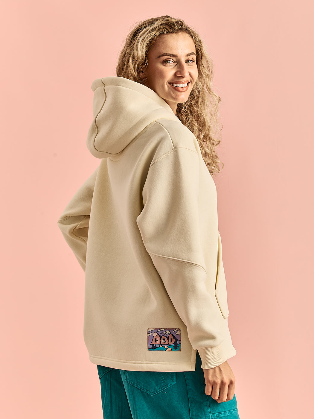 Female Model wearing the unisex hoodie, showing the arm details and the back badge