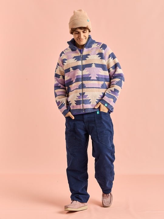 Male model shown wearing the aztec pattern knit, which has colours of Light Peach, Pale Airforce, Deep Lavender, Lavender Mist & Cream.