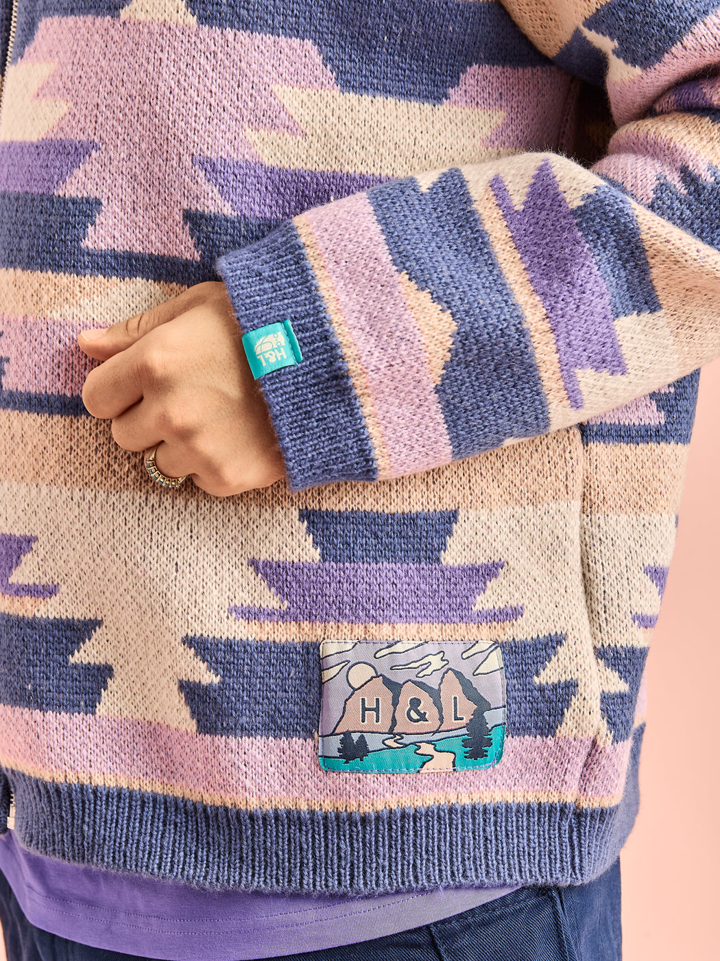 Detail shot of the aztec patterned cardigan with a branded mountain inspired badge and a tab on the cuff.