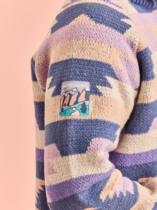 Close-up detail shot of the branded woven badge on the sleeve of the knitted jumper.