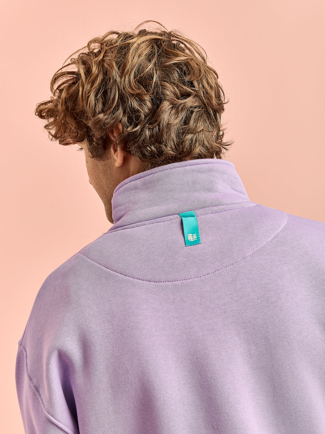 Detail shot of the teal tab on the back of the collar which is in a teal to compliment the tone of the sweatshirt