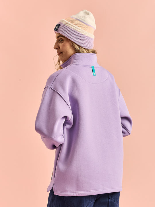 Female model shows the back of the 1/4 zip unisex sweatshirt in lavender