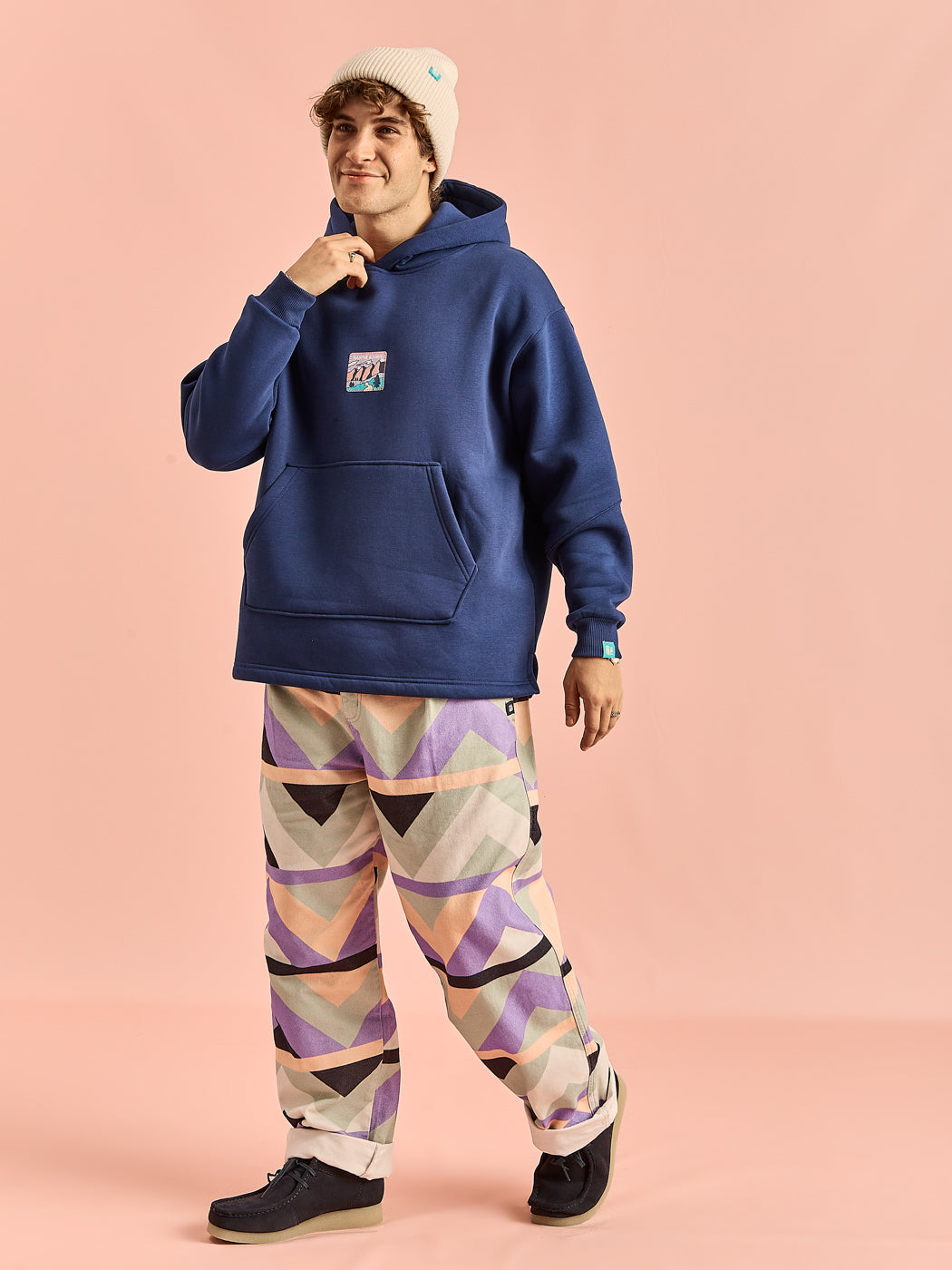 Male model wears the Ezra trousers  features shades of Cream, Navy, Lilac & Sage, these trousers stand out with their unique colour blend