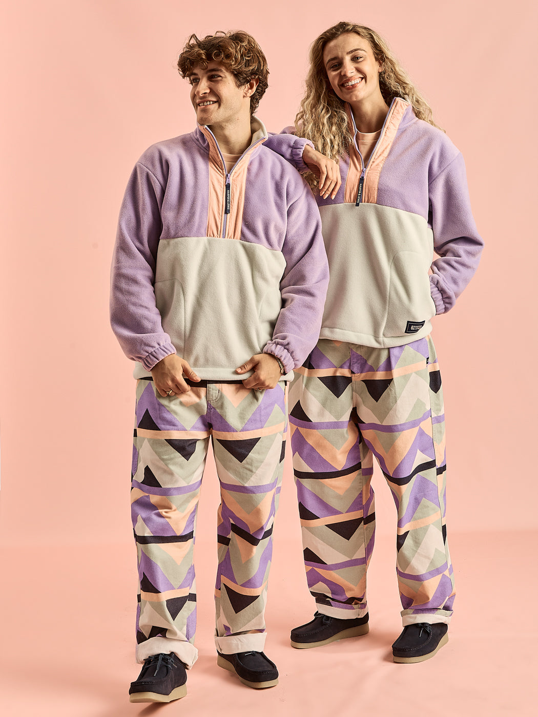Both Models wearing the Fern Fleece Jacket, featuring a mix of Light Lilac & Light Sage and a Light Peach Placket.