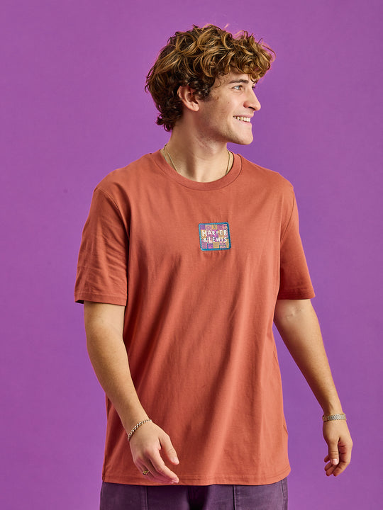 Male Model wears short sleeved t-shirt with a branded badge on the front and subtle details