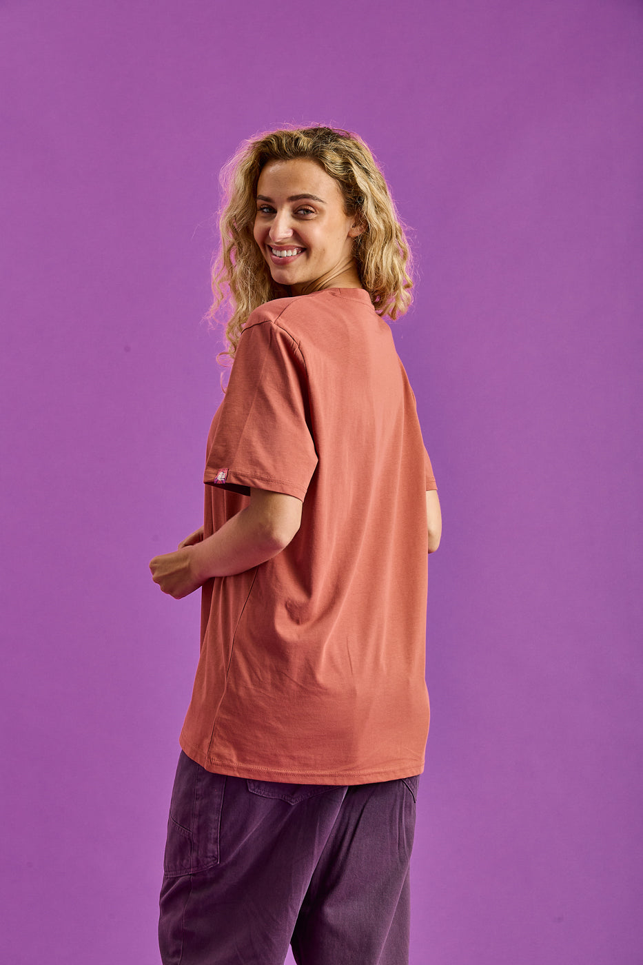 Back shot of the female model wearing the oversized t-shirt featuring a branded sleeve tab