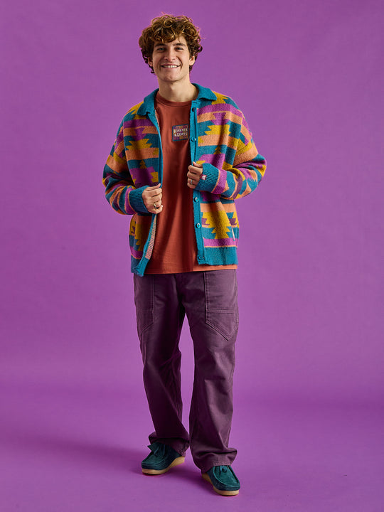The design features contrast colour collar,  ribbed cuffs and hem in teal, which subtly complements the cardigan's intricate pattern.