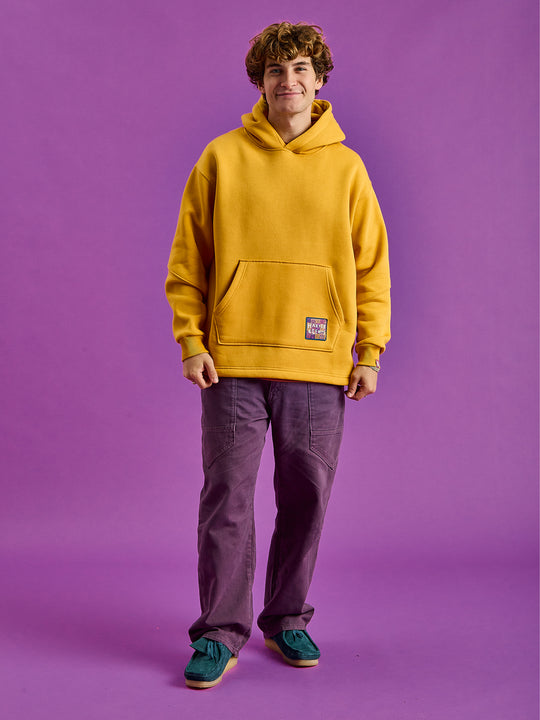 Male Model wears a mustard hooded sweatshirt. The set-in sleeves offer a classic fit, while the relaxed hem design enhances the modern appeal.