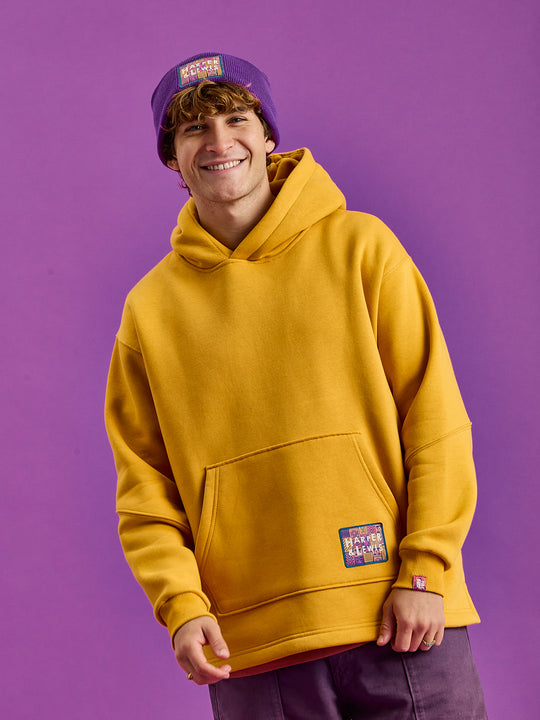 This Mustard hooded sweatshirt is adorned with a woven badge on the front and back at the relaxed hem.