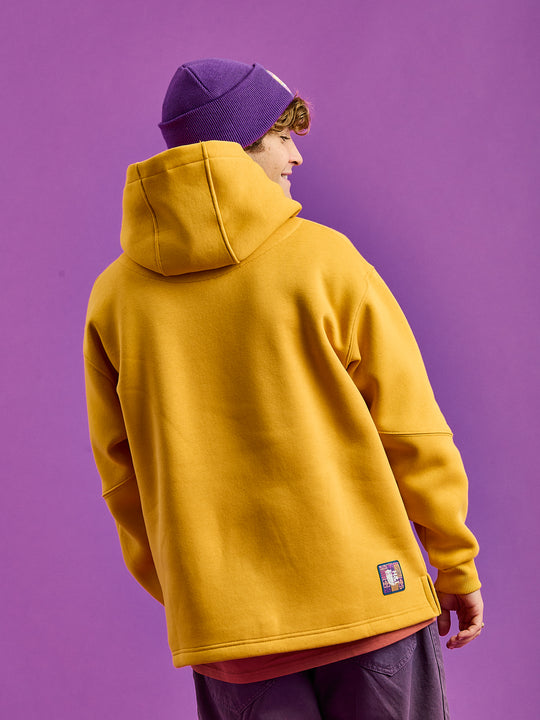 Back shot of the mustard yellow oversized hoodie with the branded patch on the hem.