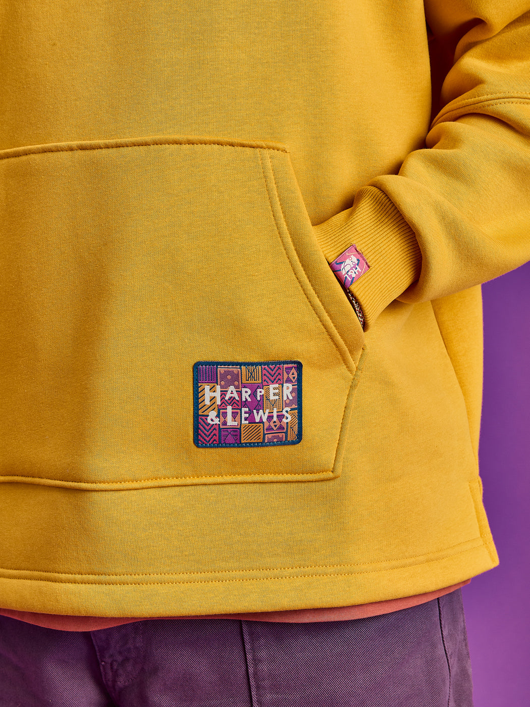 Detail shot of the branded woven badge on the front pocket with a branded tab on the cuff.