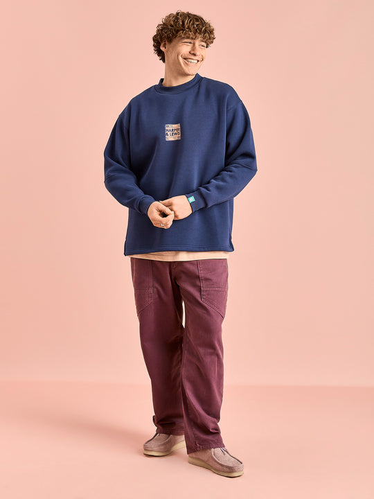 Male Model wears the Unisex sweat which is made from a fleece-back jersey fabric composed of 65% Cotton and 35% Polyester.