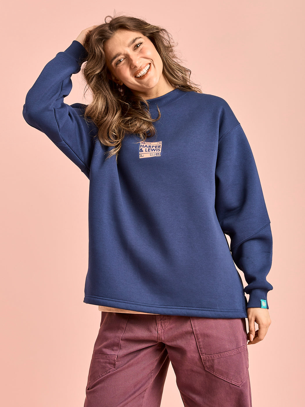 Female model wears the oversized sweater which features a branded front graphic on the chest.