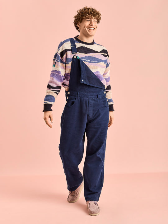 Male model wears the navy dungarees which features adjustable brace straps