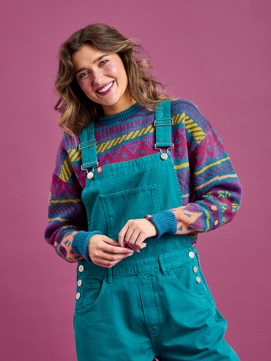 Female model wears the unisex dungarees, which features a front bib pocket