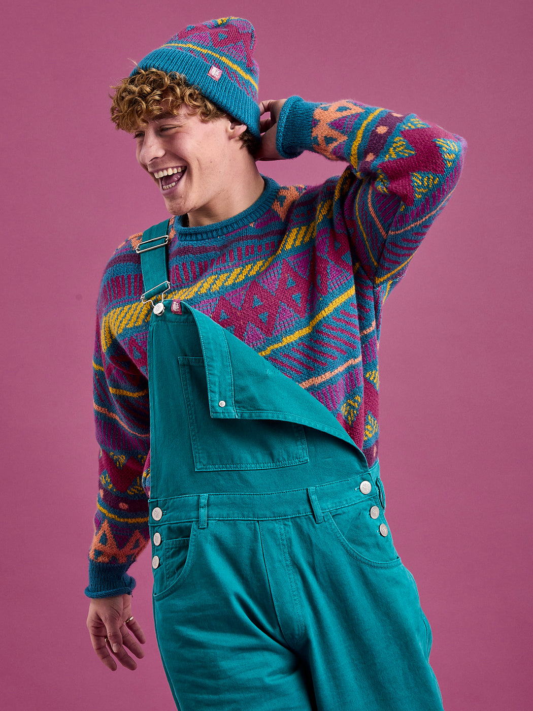 Male model wears the dungarees with one adjustable strap down to show how they can be worn casually