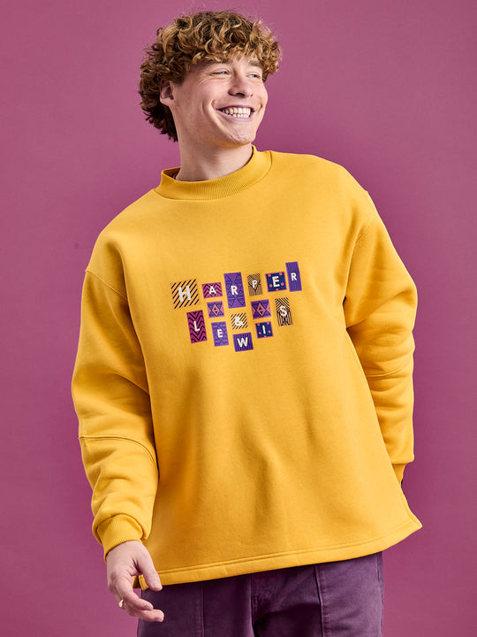 Male Model wears the oversized sweatshirt in a Mustard yellow colour.