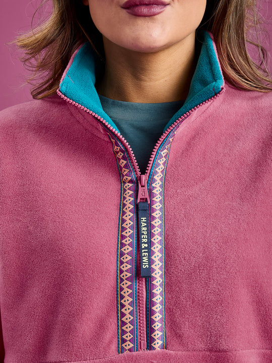 Close up detail of the Fleece Jacket, this shows the branded zip puller, the teal inside collar and the Aztec Wave Pattern woven tape around the zip.