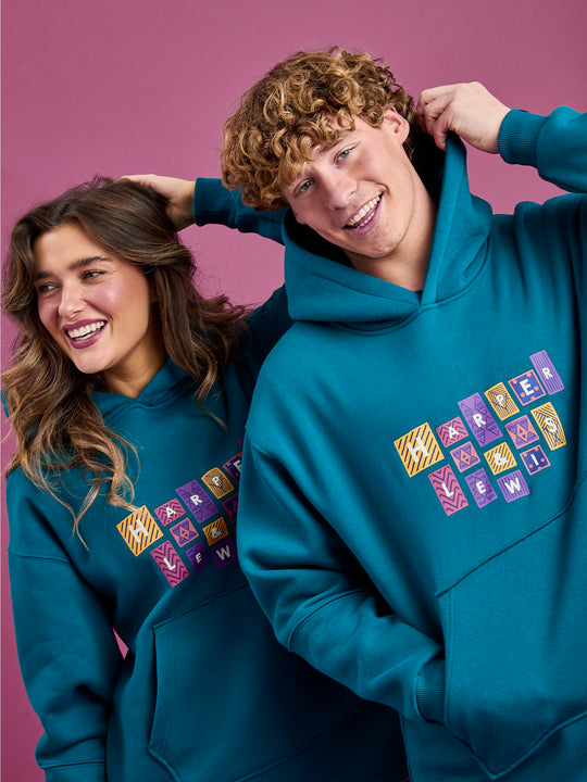 Both models wearing the teal oversized hooded sweater, showing the hood.