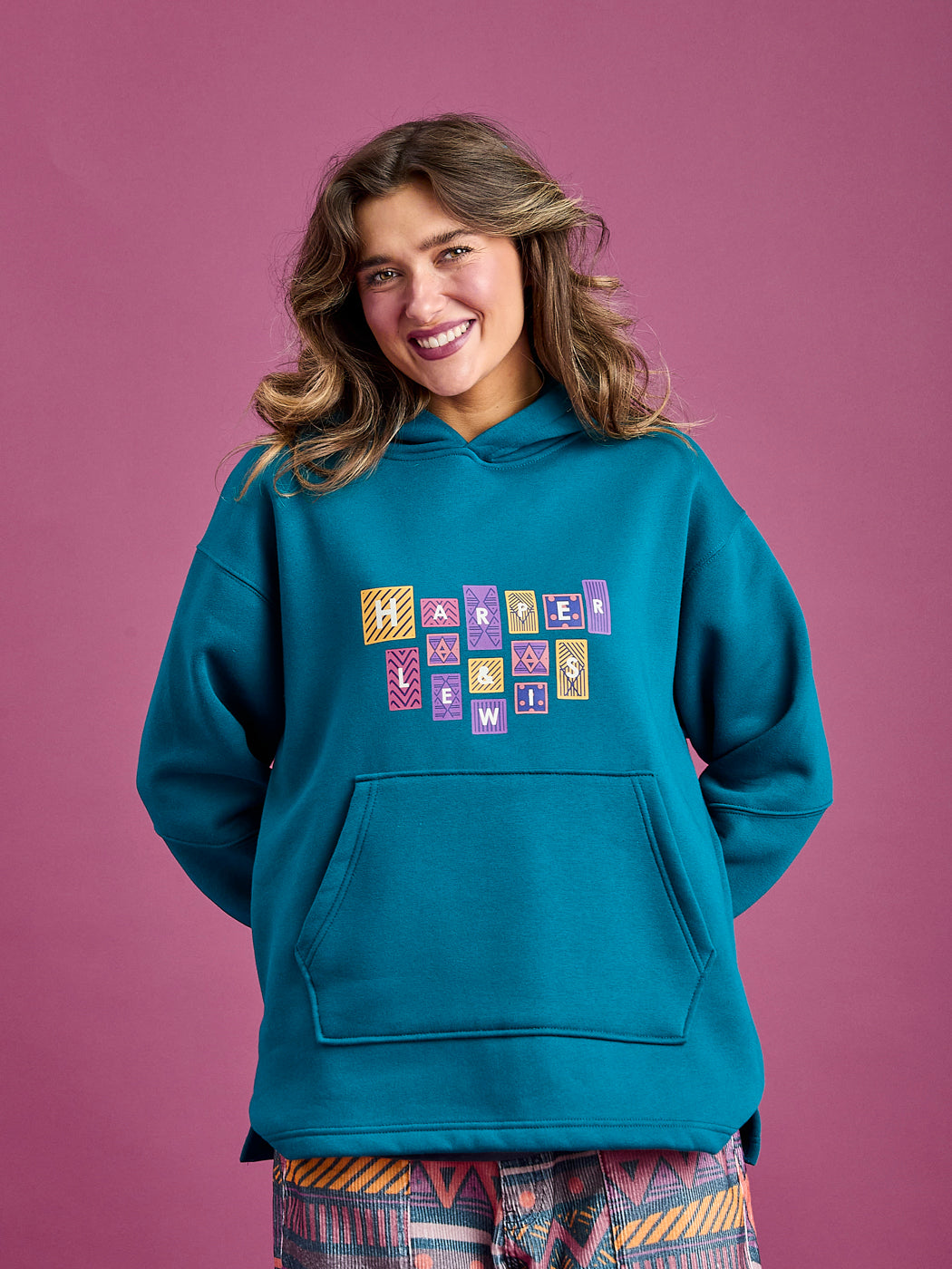 Female model wears the Garnet Hoodie in Teal, featuring a striking front graphic.