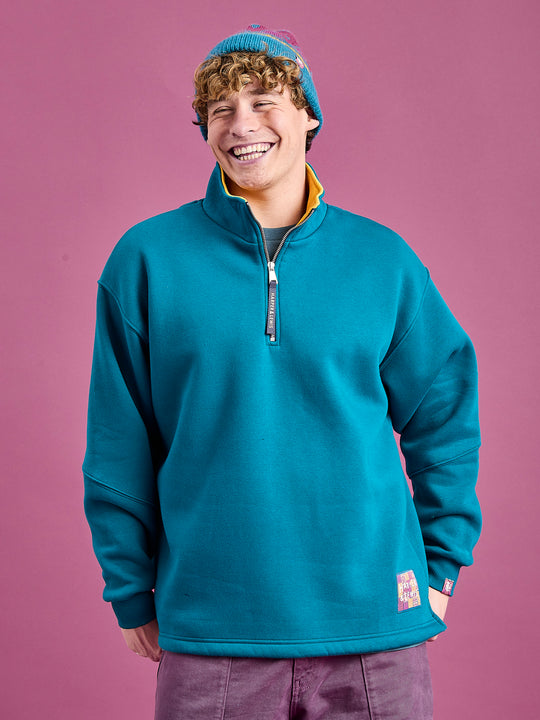 Male Model wearing the Teal jumper, this features a zipped neck and subtle branding all throughout.