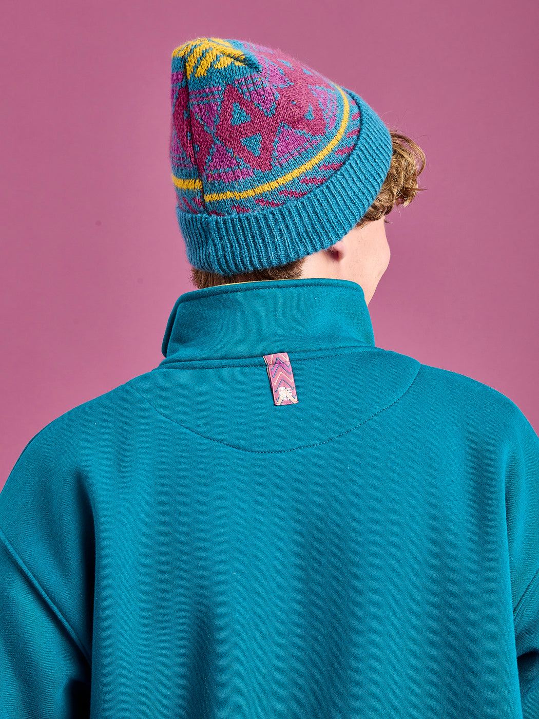 Detail shot of the back neck branded tab on the teal green sweater