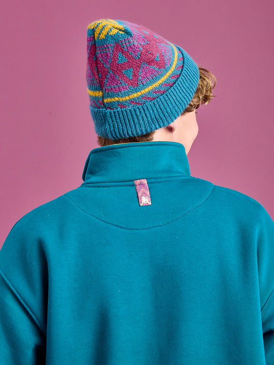Detail shot of the back neck branded tab on the teal green sweater