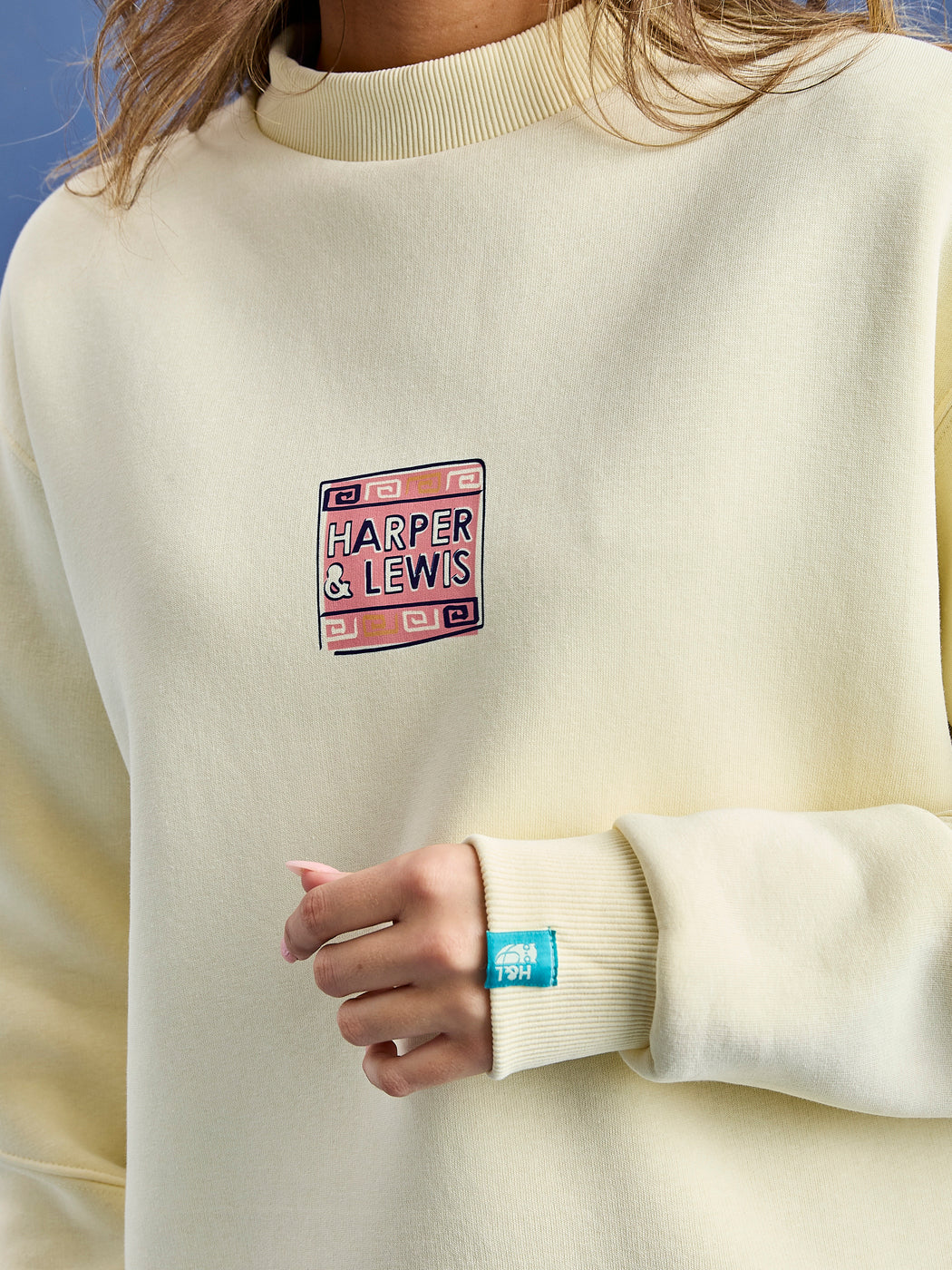 Detail shot of the atlas sweater which features a retro branded print on the front chest and a branded tab on the cuff.