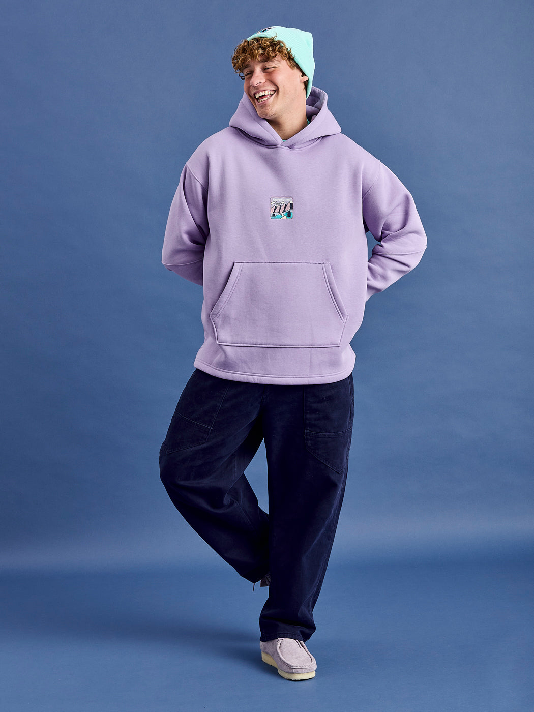 Male Model wears a oversized unisex hoodie with a released hem.