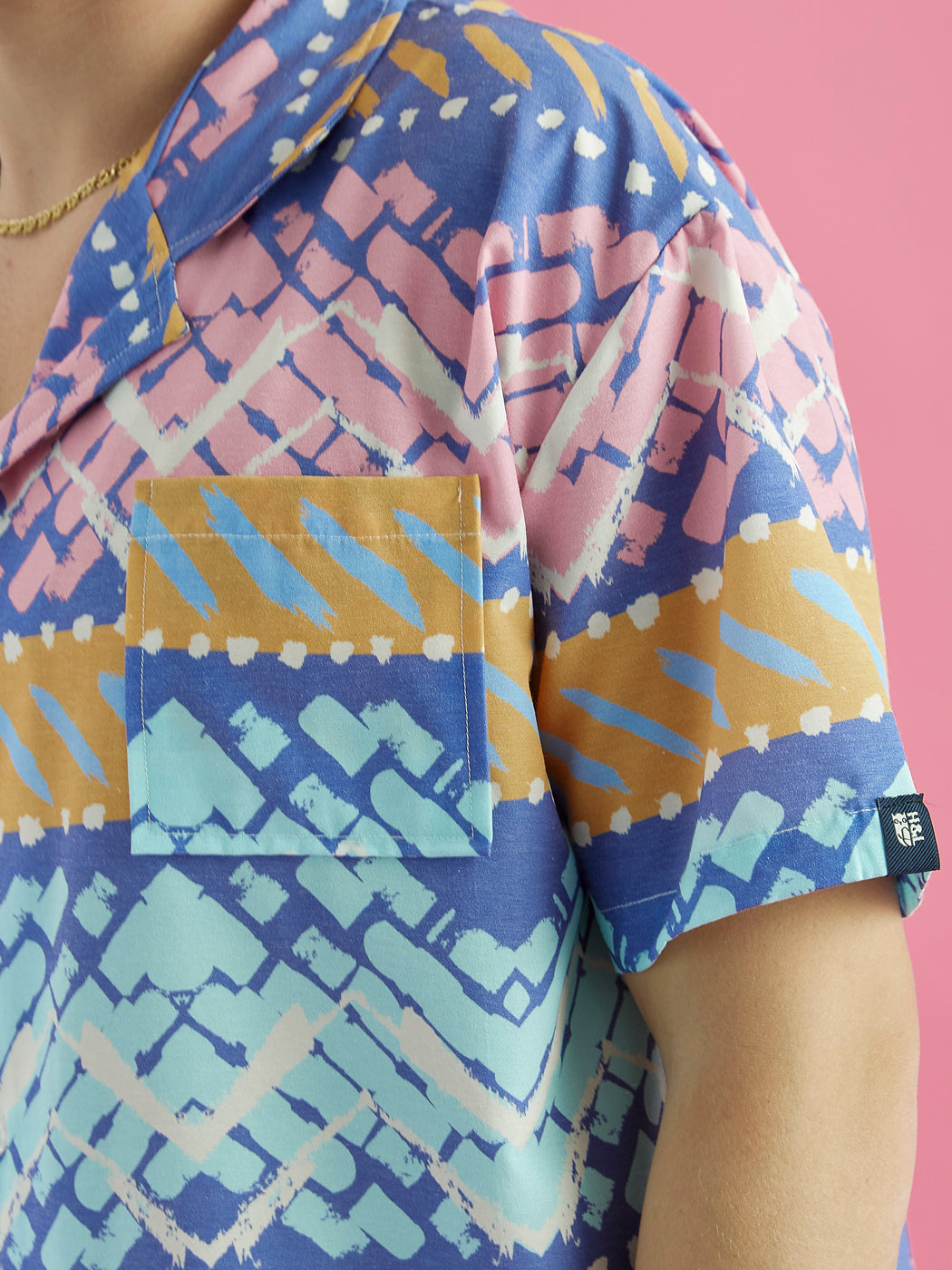 Detail image of the pocket, collar and woven tab on the button up short sleeve shirt.