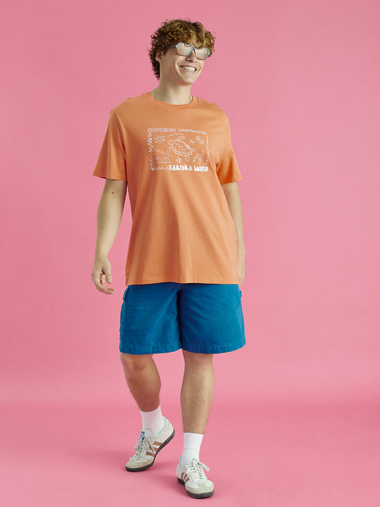 Male model wearing this Apricot tshirt casually with some patterned shorts.