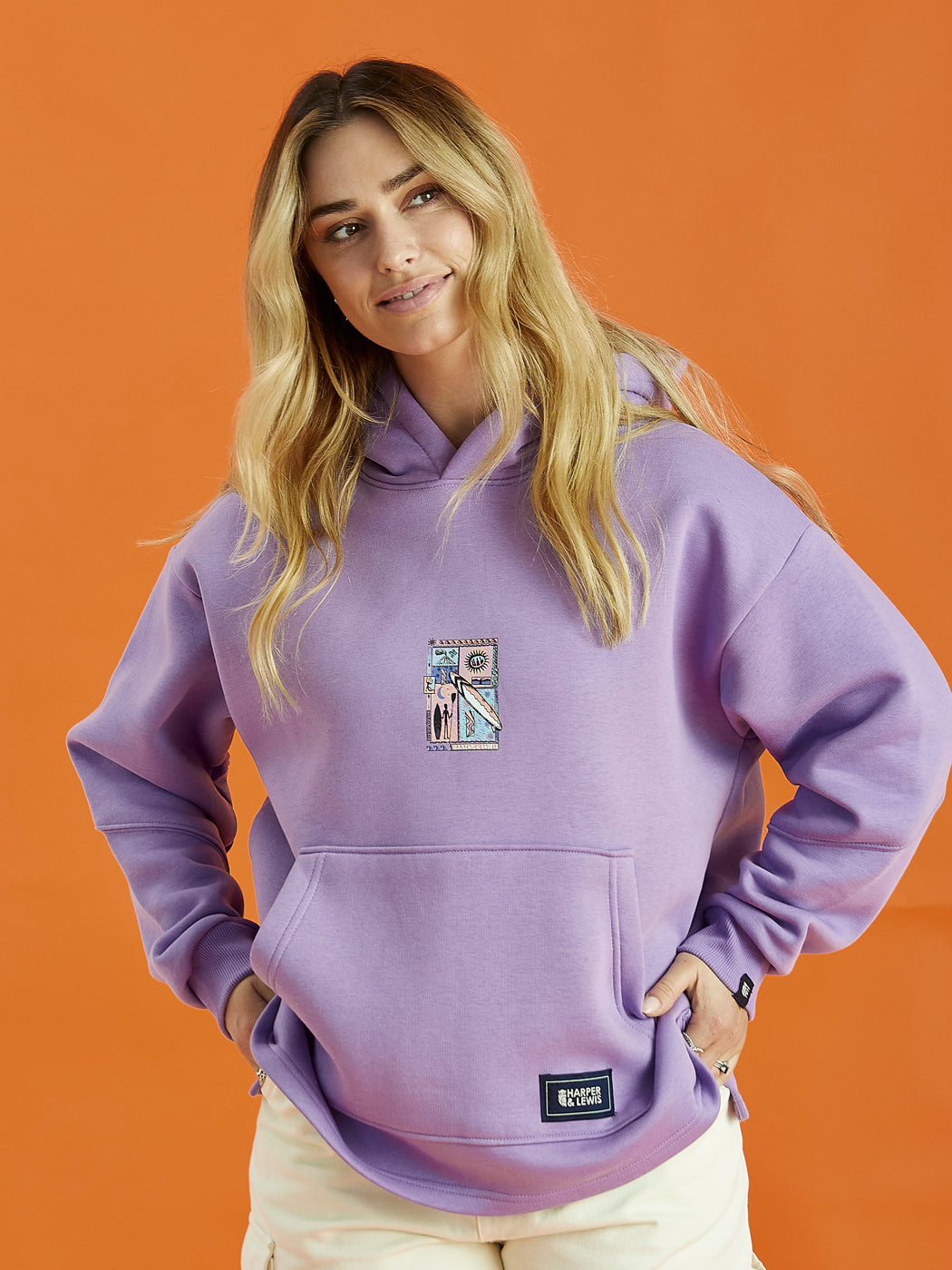 Female Model wearing the Cruz hoodie in purple, featuring the tribal surf graphic on the centre of the front of the hoodie.