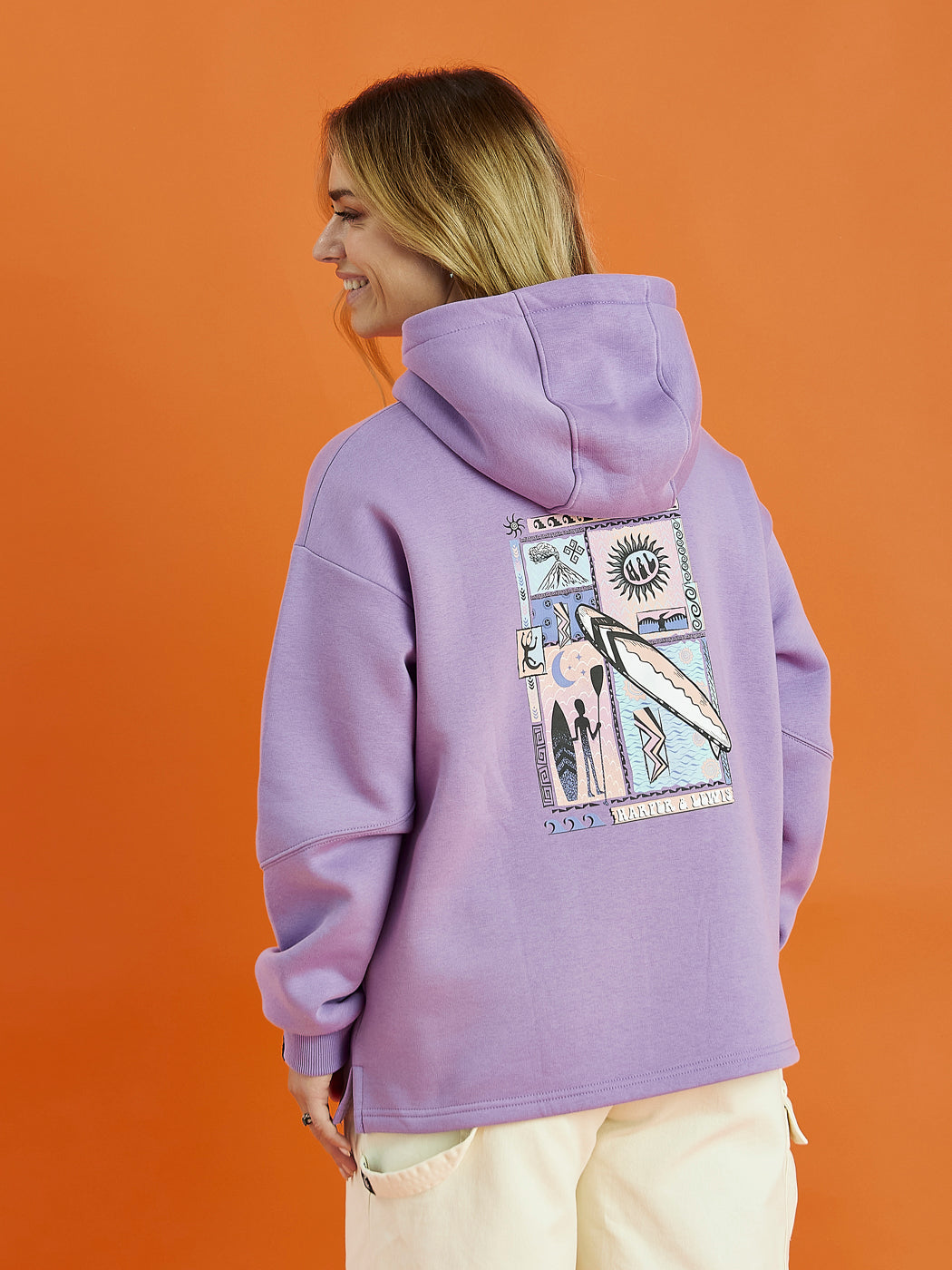 Back shot of the female model wearing the Cruz Hoodie in Purple. This shows the seams on the sleeves, and the back graphic detail.