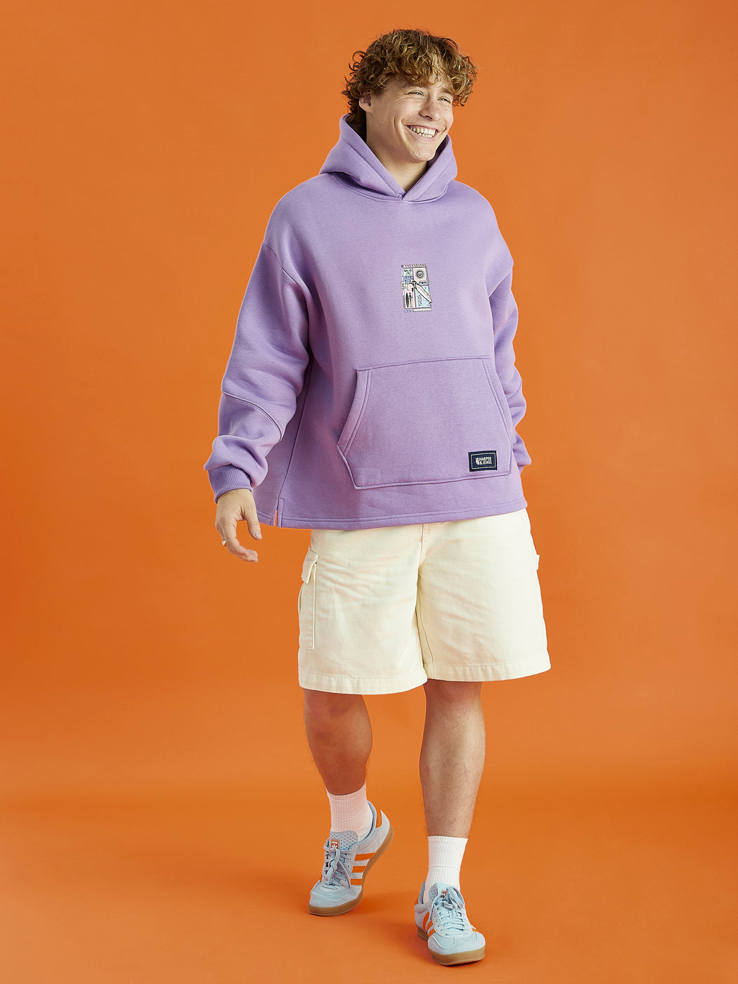 Male Model wearing the Cruz Hoodie in Purple, which is an oversized hooded sweatshirt with an open hem on the bottom.