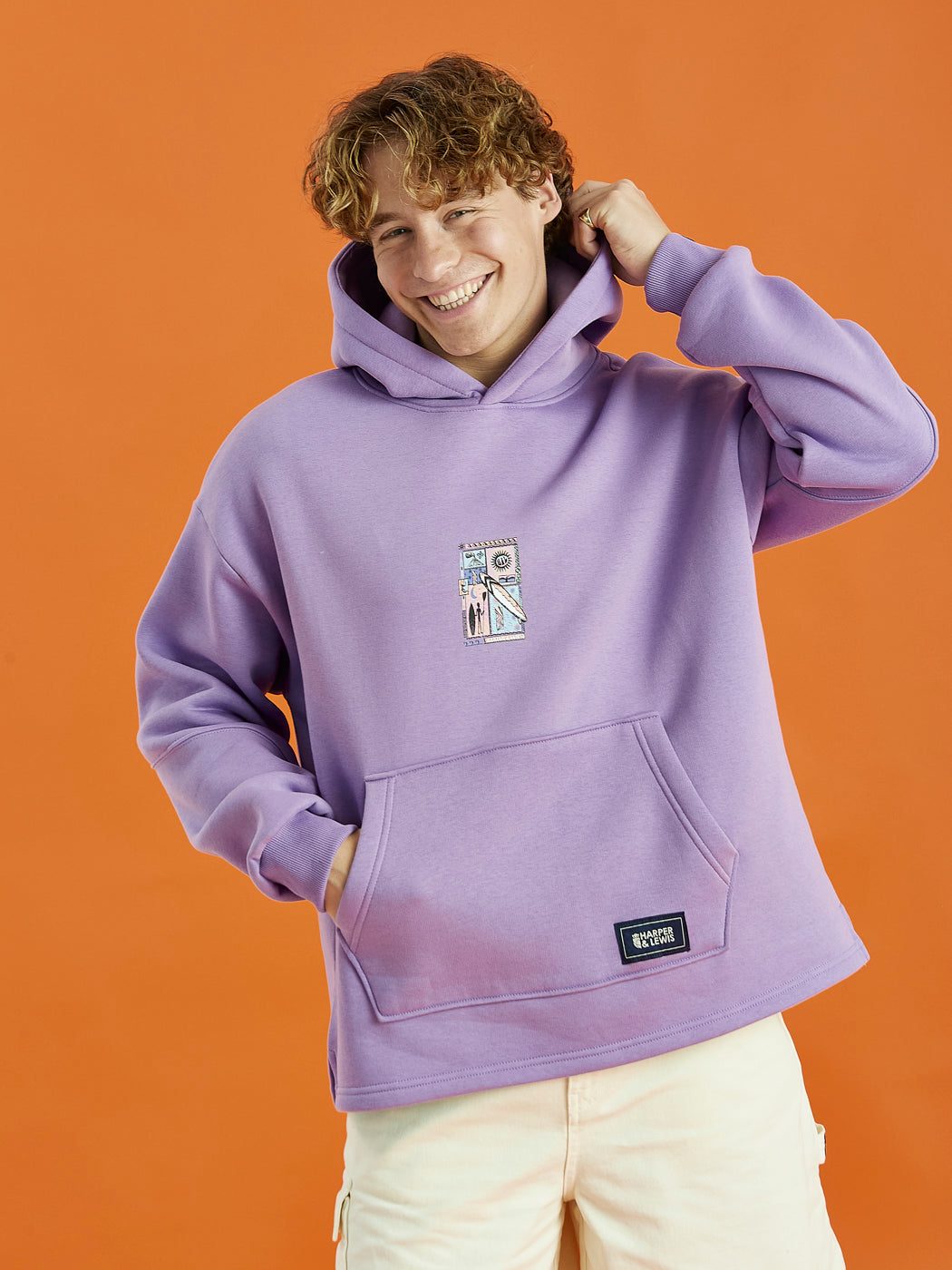 Male Model wearing the Cruz hoodie in Purple, this is adorned with a Tribal Graphic on the back and a Harper & Lewis emblem on the front, a nod to our vintage-inspired roots.