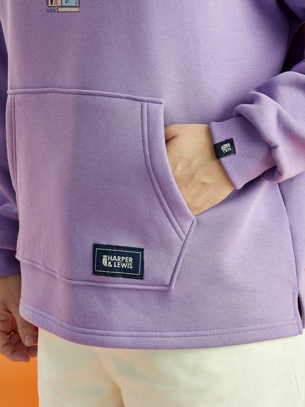 Details of the woven badges that are on the front kangaroo pocket and the left sleeve in navy.