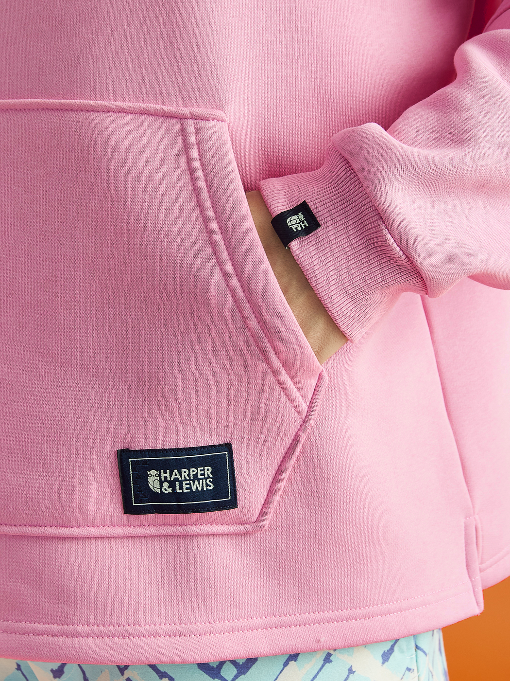 Details of the woven badges that are on the front kangaroo pocket and the left sleeve in navy.