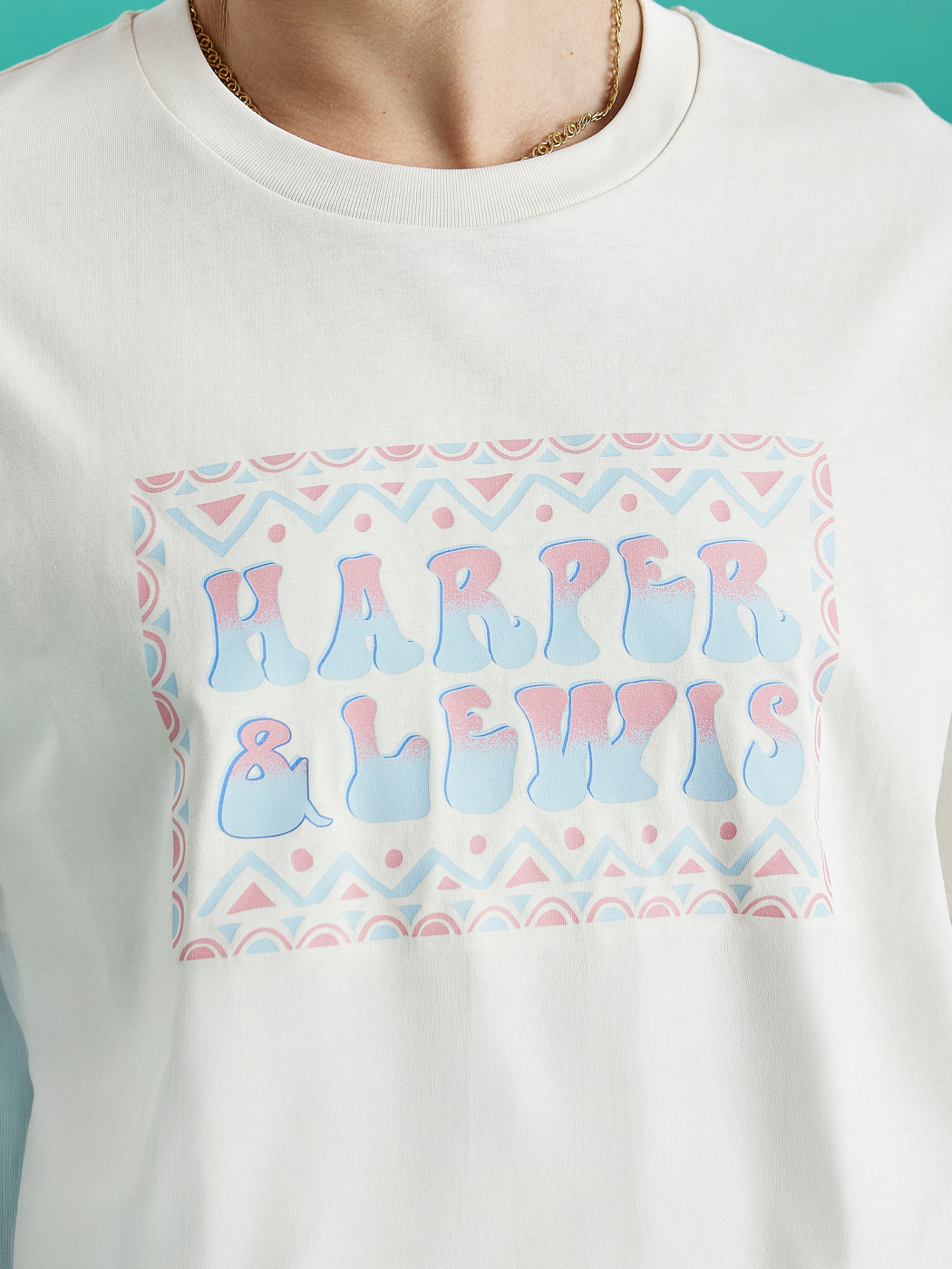 Close up image of the design on the Taran tee, this features an abstract spell out design with blue and pink.