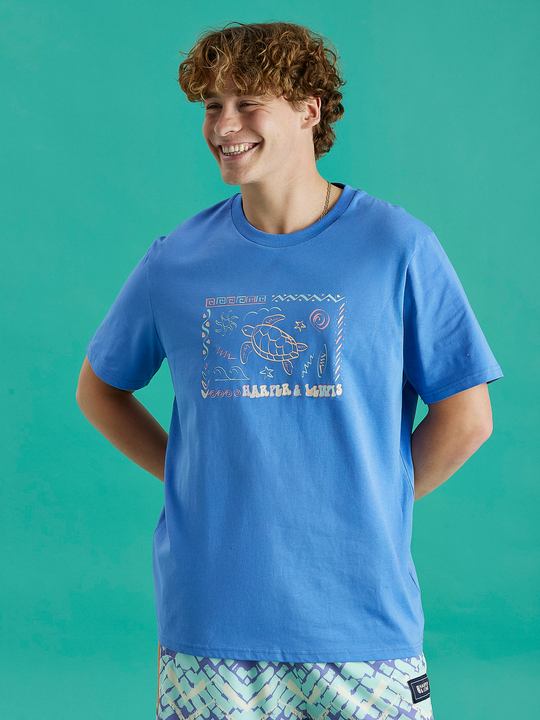 Male Model wearing the relaxed fit Surya tee in Royal Blue, this tee features a big front chest logo design.