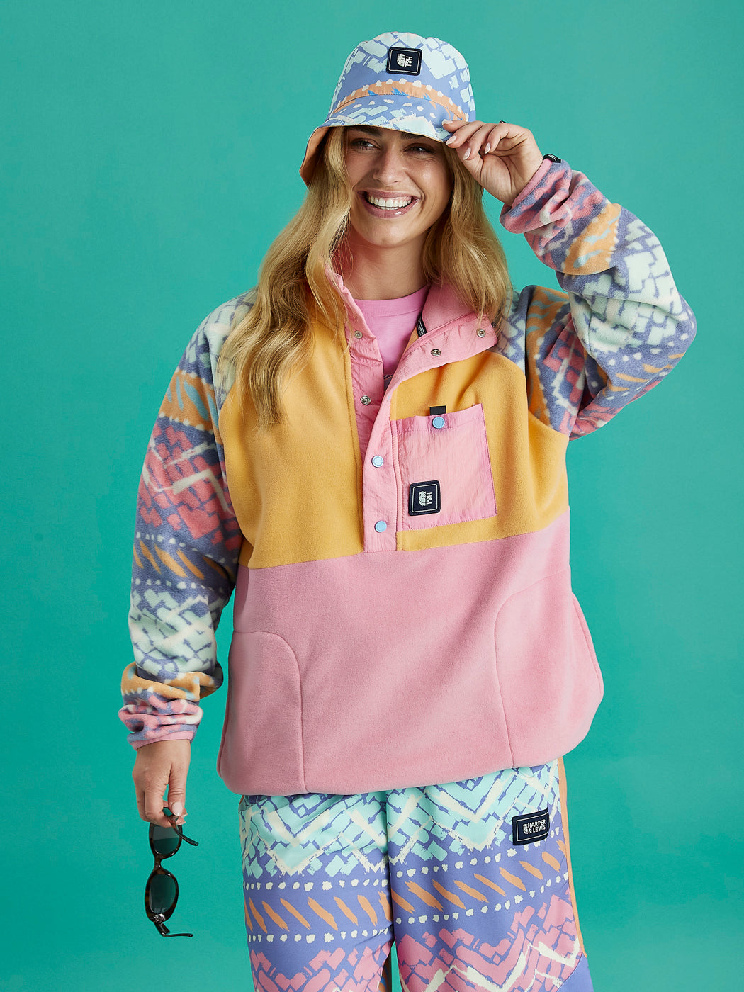 Front view of the Sutton Retro Popper Neck Fleece by Harper & Lewis, featuring an all-over multicoloured retro pattern on soft fleece fabric, with a pink snap-button placket and collar.