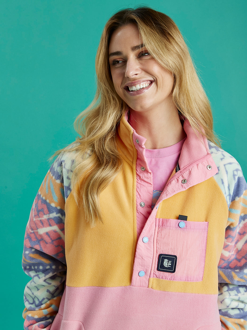 A woman wearing a pink and yellow fleece jacket, showcasing the vibrant colours and texture of the fabric.