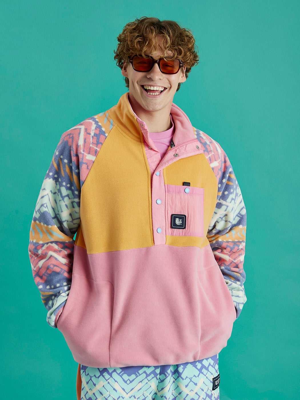 Male Model wears the Sutton fleece inspired by 90's culture, with vibrant colours and festival patterns.