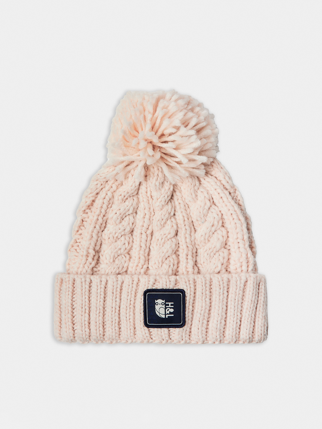 The classic cable knit pattern adds texture and depth, while the self-coloured pom pom gives it a classic touch.