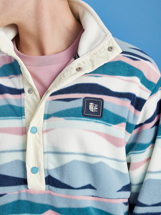 Detail shot of the blue buttons on the popper neck fastening on the oversized unisex fleece.